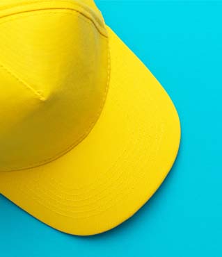 Top view of yellow baseball cap over the blue turquoise background. Flat lay mock-up image of unisex bright yellow cap. Photo of yellow baseball hat with copy space.